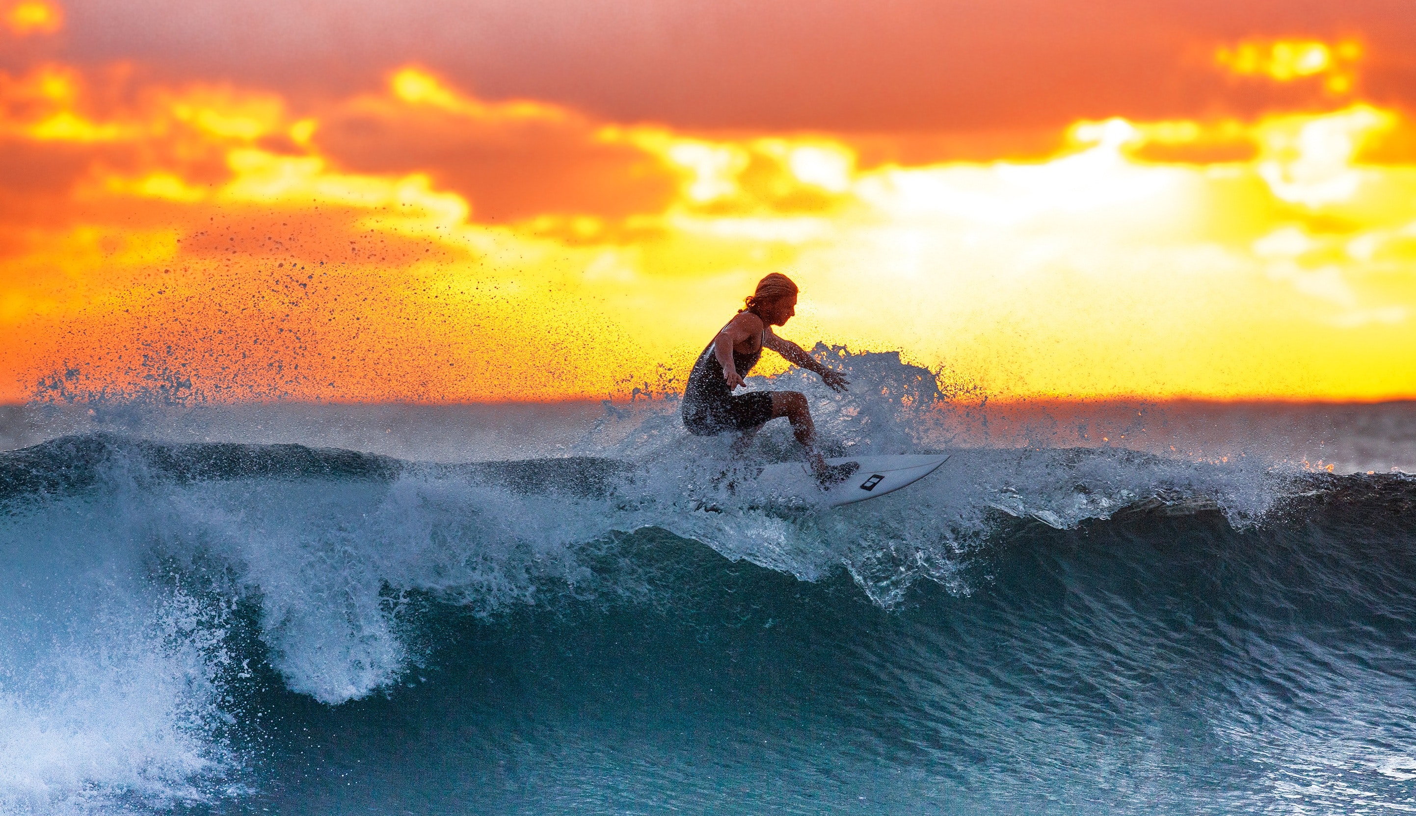 guy surfing in cornwall with sunset